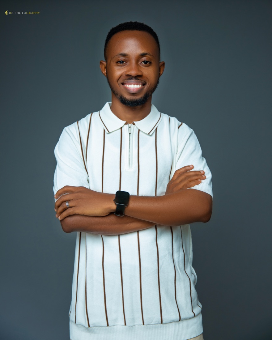 David Effiong smiling, arms folded, in a white striped shirt